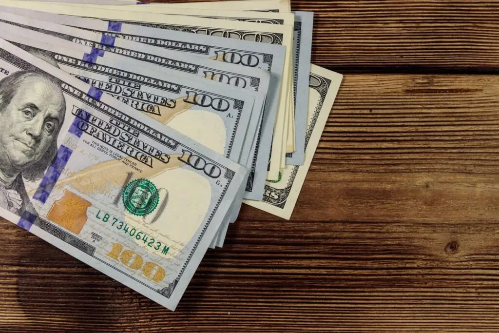 A pile of money sitting on top of a wooden table.