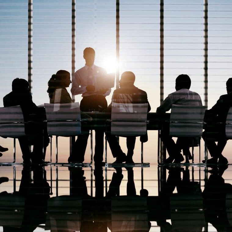 A group of people sitting at a table in front of the sun.